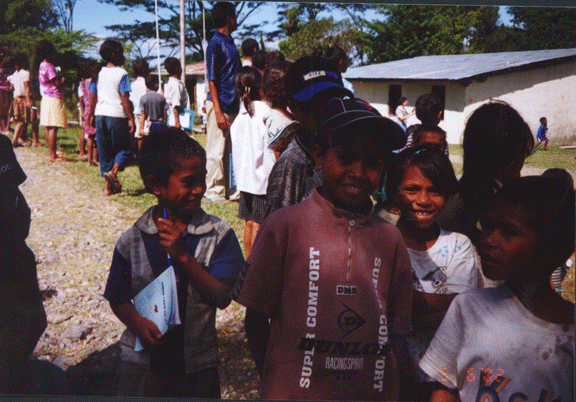 19 kids near mobile clinic in Soro, frisbee throwing in background